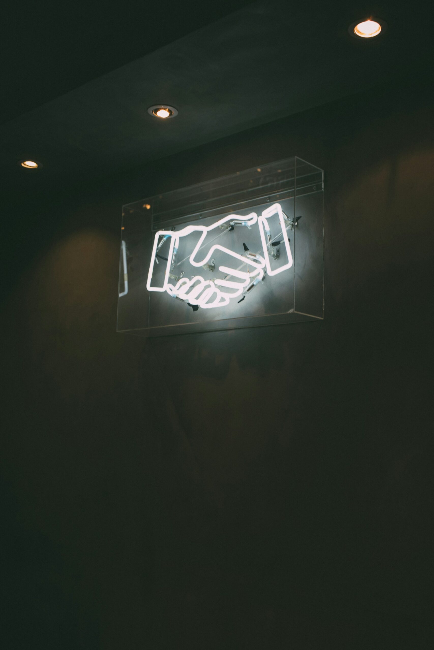 a photograph of a neon sign depicting a handshake - collaborations concept