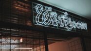 a photograph of a white neon sign that states "The Workroom"; co-working and HR concept