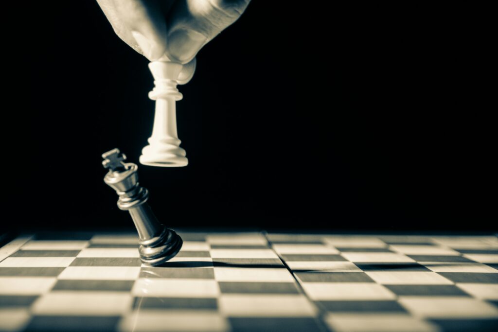 black and white photograph of a chess board and white pawn defeating black; risks management concept