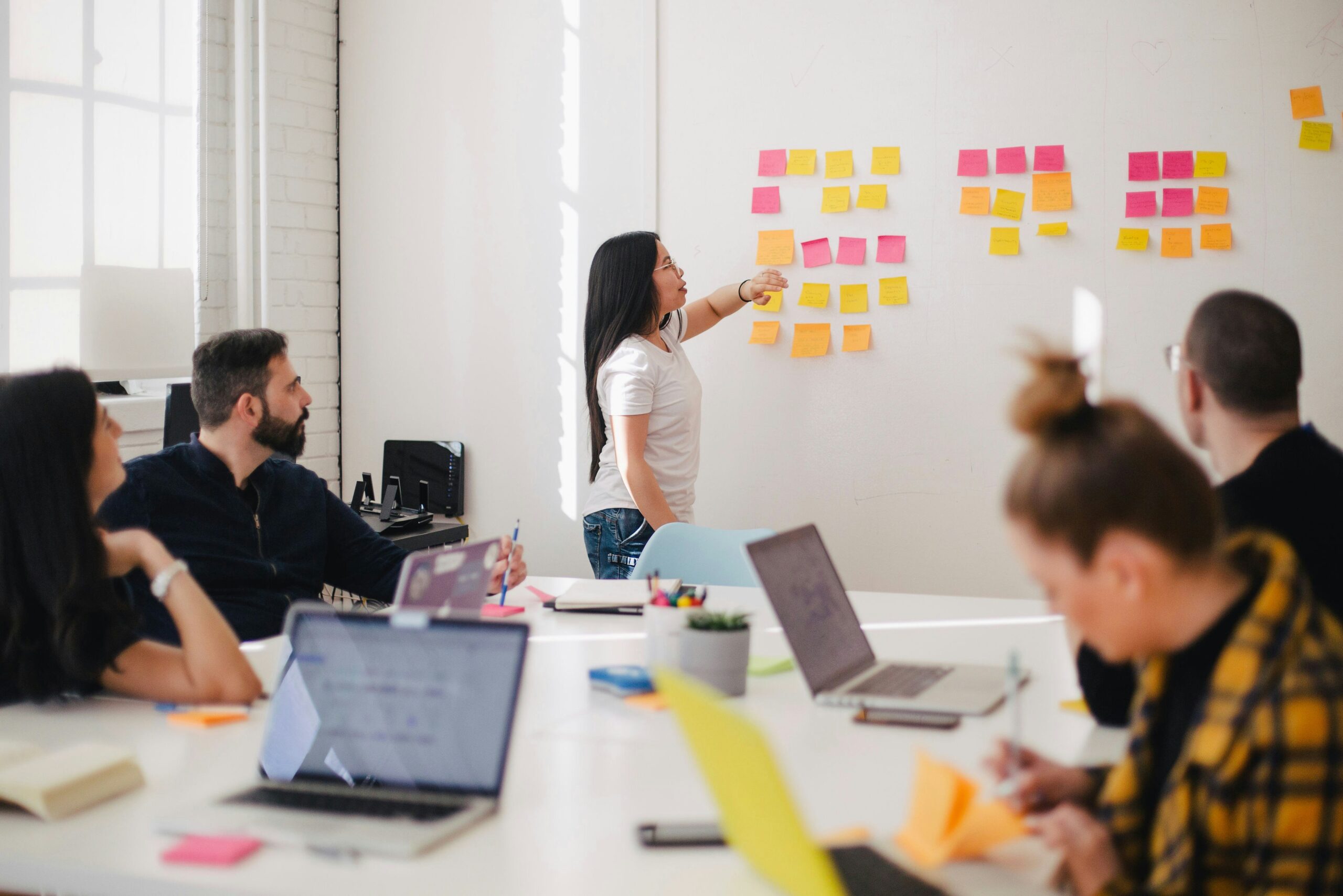 people gathered around a table with laptops and a whiteboard| Scaling up with self-paced and guided SAP learning