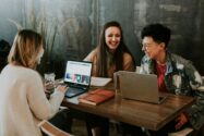 three women using computers and laughing while talking