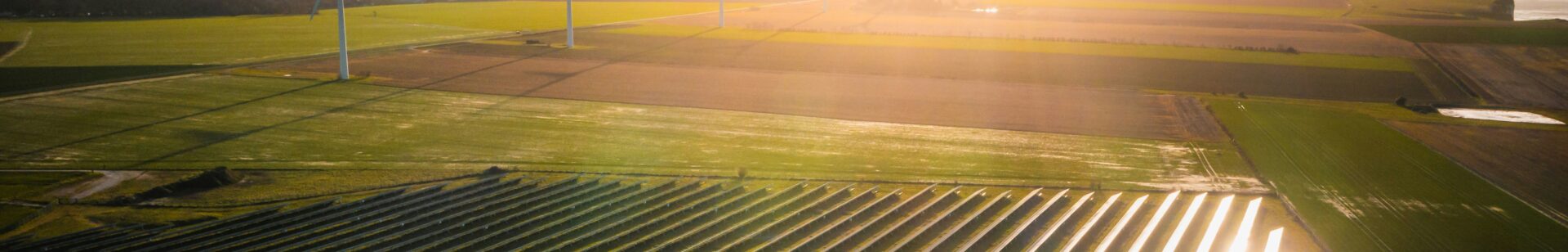 a field with wind turbines and solar panels