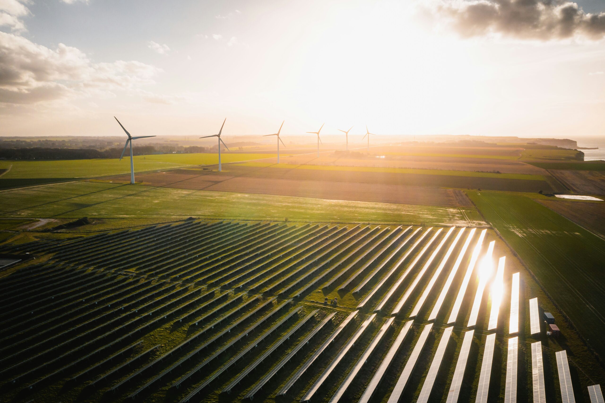 a field with wind turbines and solar panels