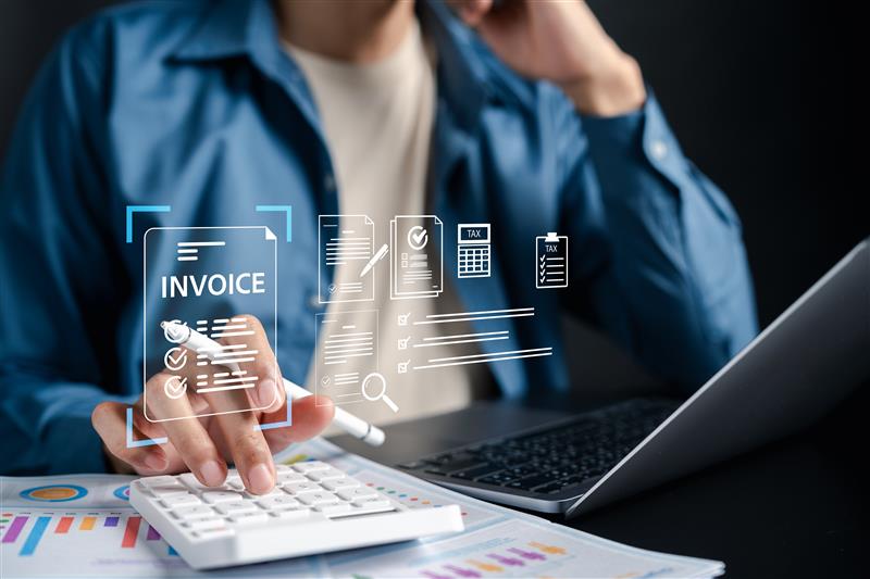 Professional reviewing digital invoice interface on laptop and calculator, representing SAP mandated e-invoicing compliance and electronic tax reporting.