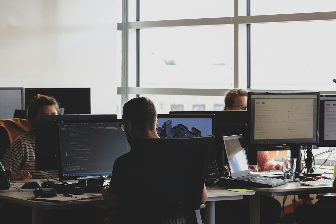Developers working at computer workstations in an office environment during enterprise software and security monitoring activities.