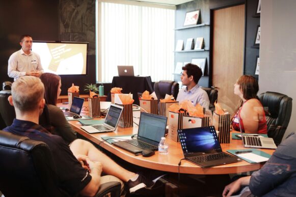 A diverse group of technology leaders and developers at a conference table, with laptops, observing a presentation screen titled Development with SAP to improve operational efficiency and self-fund innovation.