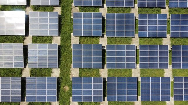 Aerial view of blue solar panels in a solar energy field, representing financial and ESG data in a modern environment.