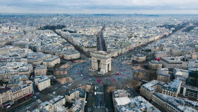 Aerial view of the Arc de Triomphe in Paris showing urban infrastructure, road networks, and city layout.