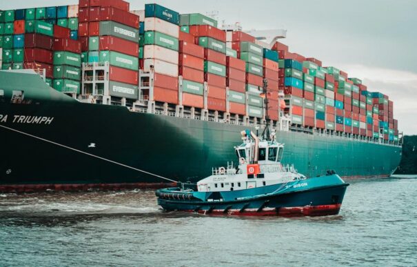 Container ship being guided by a tugboat, representing value movement across intercompany supply chains.