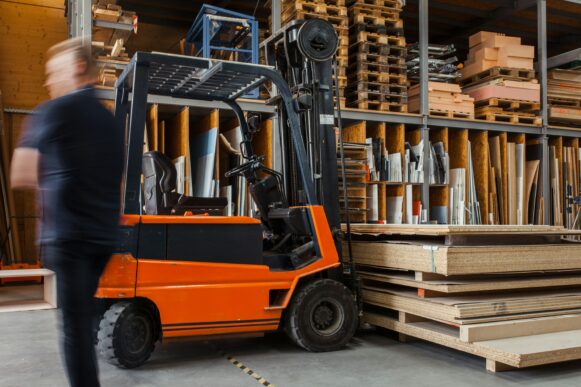 Worker with a forklift in a large carpentry workshop with many timbers in the background._SAP Ariba next generation