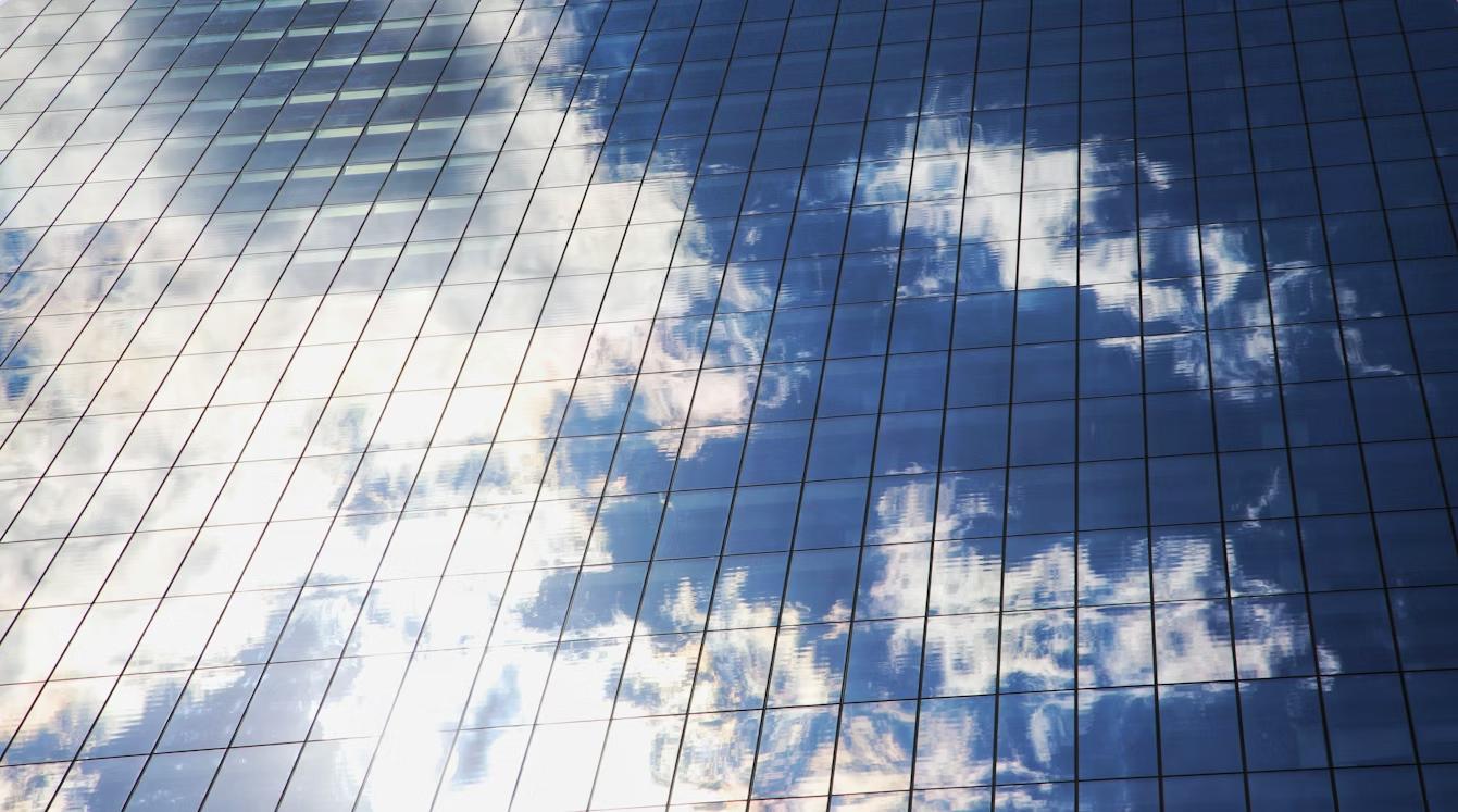 Cloud reflecting on a glass office building, symbolizing SAP Business Technology Platform cloud environments used for enterprise applications and cybersecurity extensions.