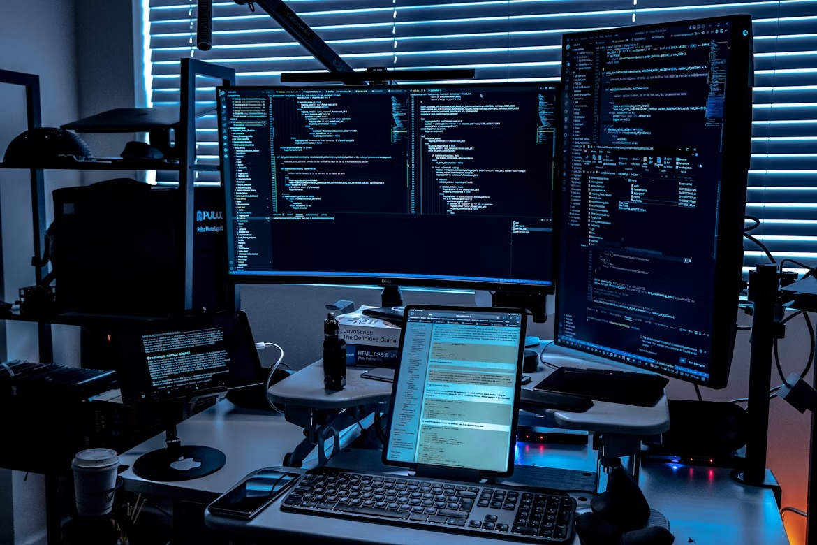 Enterprise IT monitoring setup with multiple screens displaying code and system data, representing SAP security patching and authorization risk across SAP environments.