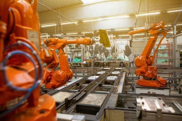 Orange industrial robotic arms operating on an automated manufacturing assembly line in a smart factory