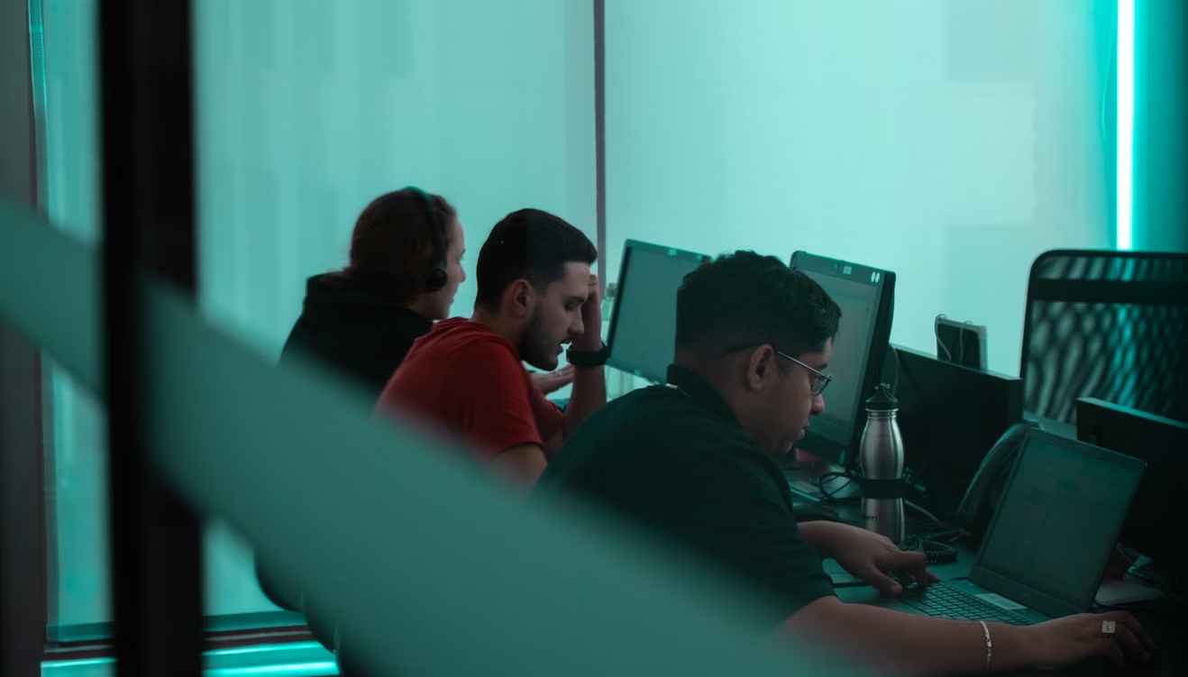 People working at a computer in a dark office, representing SAP security and GRC execution across modern enterprise systems.