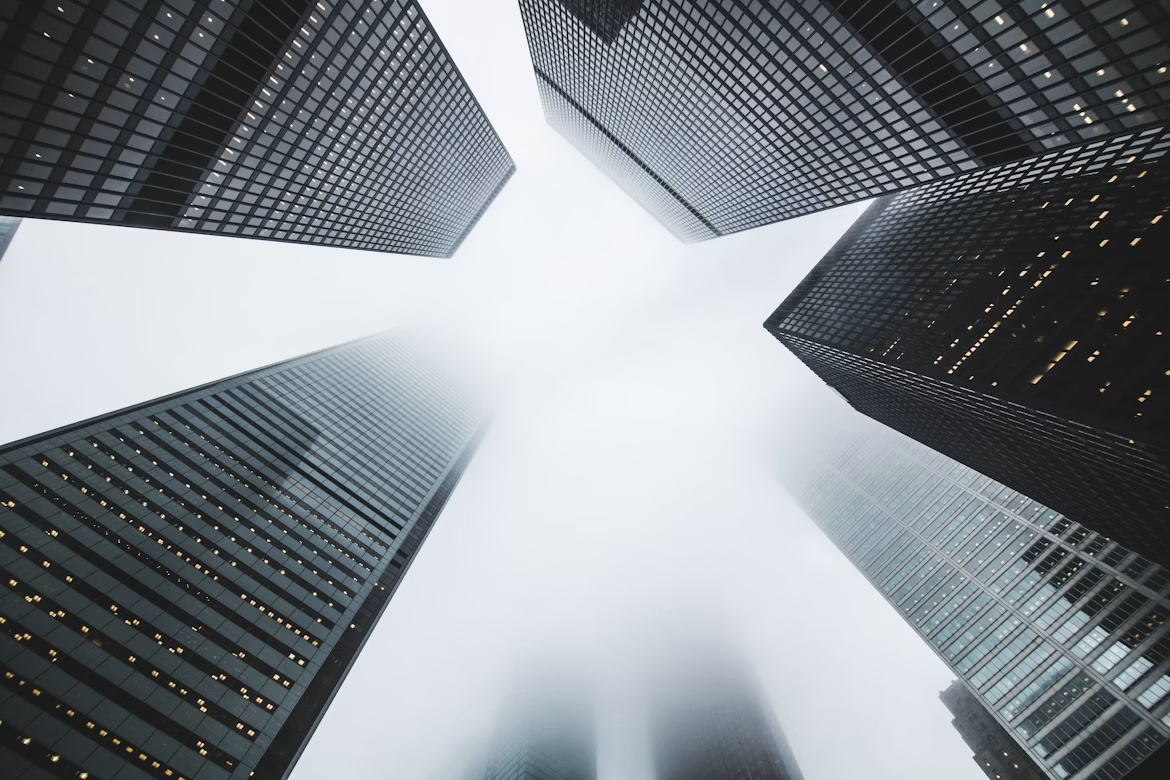 Looking up at tall office buildings in fog, representing executive accountability and enterprise pricing control.