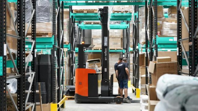 Warehouse worker operating a forklift in a distribution center, representing pricing execution across ERP and order-to-cash workflows.