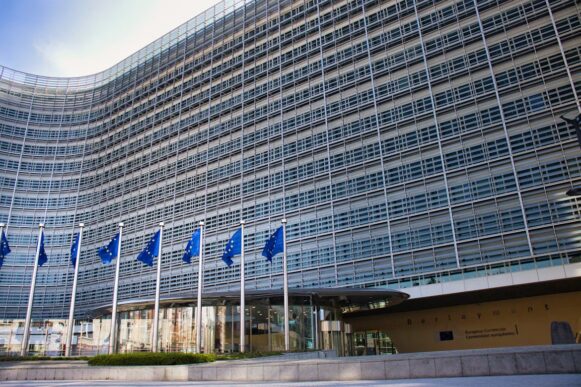 European Commission Berlaymont building in Brussels with EU flags outside.