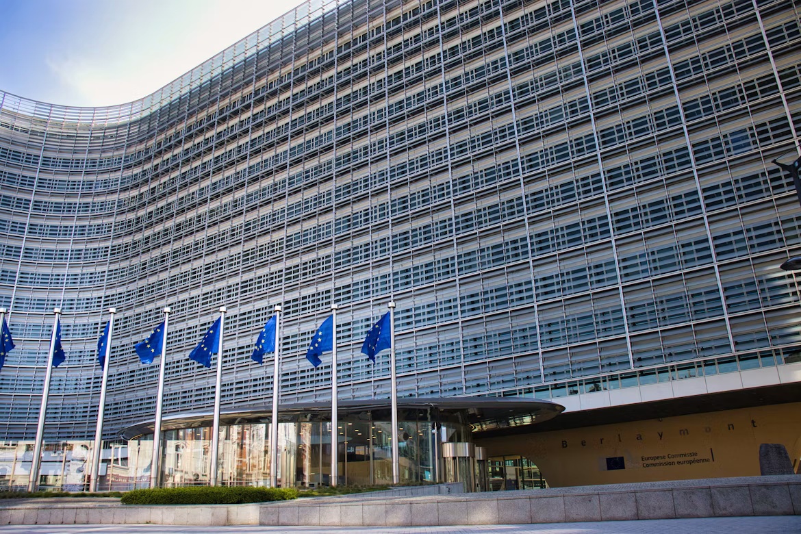 European Commission Berlaymont building in Brussels with EU flags outside.