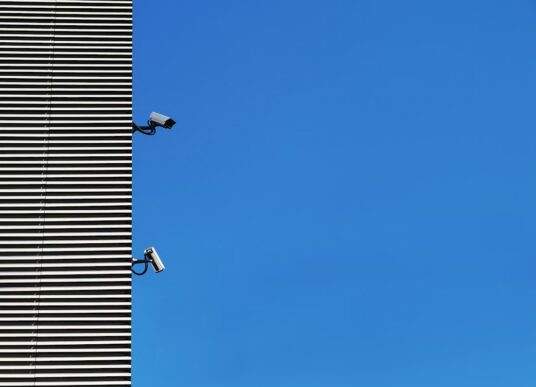 Security monitoring equipment on a building against a blue sky, representing SAP cloud security risks around AWS-based modernization.