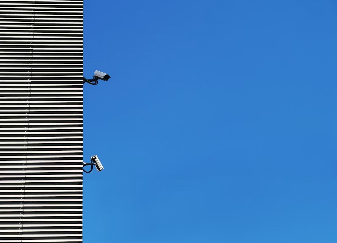 Security monitoring equipment on a building against a blue sky, representing SAP cloud security risks around AWS-based modernization.