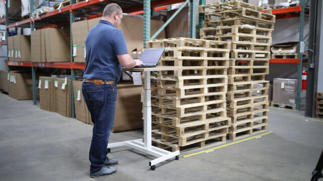 Warehouse professional using a laptop to manage procurement and workforce operations