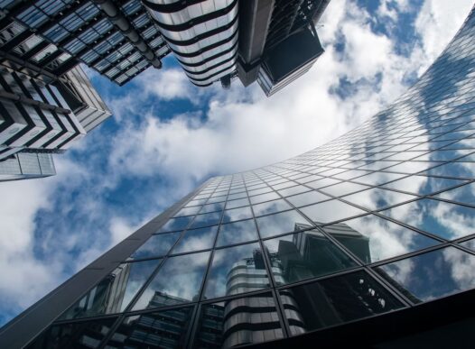 Modern glass office towers viewed from below, reflecting clouds and the city skyline for an article on UiPath Maestro Case and enterprise workflow orchestration.