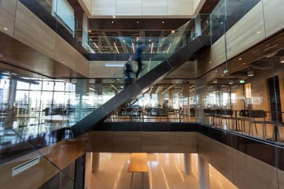 Modern multi-story building interior with glass staircase and open workspace floors representing Planon smart sustainable building management integrated with SAP S/4HANA real estate and facilities