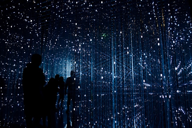 Silhouetted figures standing inside an immersive field of cascading light points, evoking SAP teams navigating thousands of changes across hybrid S/4HANA landscapes