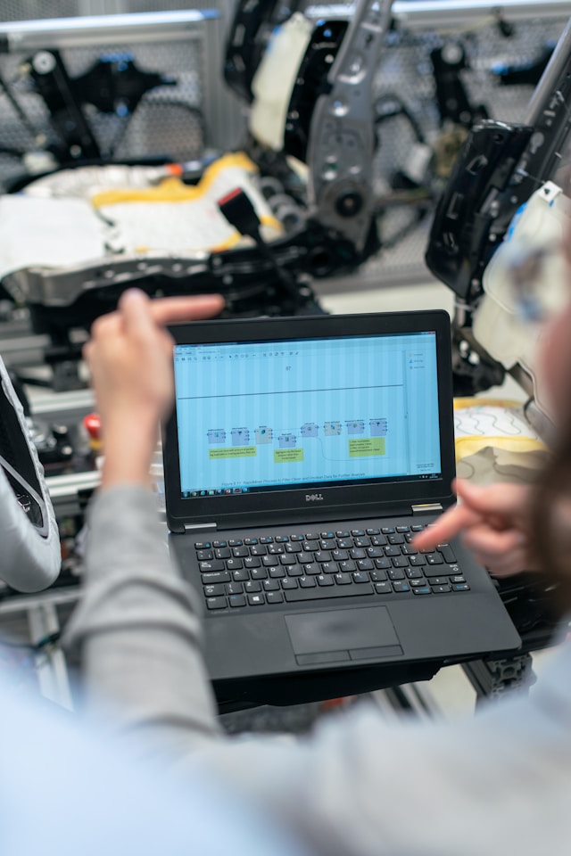 Engineer reviewing a process flow diagram on a laptop inside a manufacturing environment, illustrating automated ServiceNow to SAP incident and case workflows