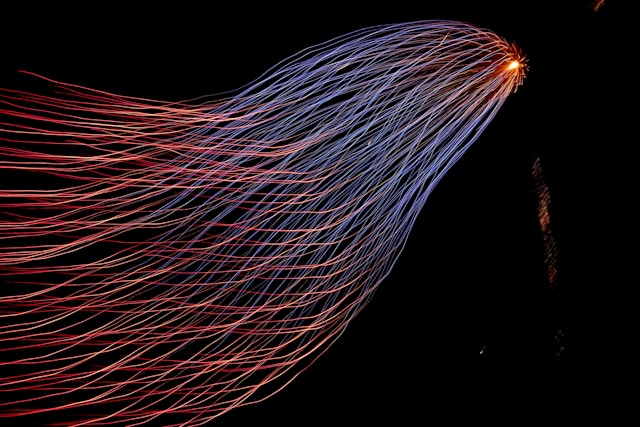 Long-exposure light trails in red and blue streaming toward a single bright point on a dark background, symbolizing SAP data flows converging during migration to a target system.