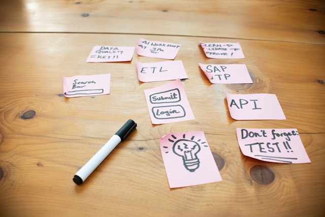 Pink sticky notes on a wooden table mapping an SAP BTP project plan, with notes for API, ETL, data quality, AI workshop, and clean core validation—illustrating clean core and integration planning for the SAP Business AI Platform.