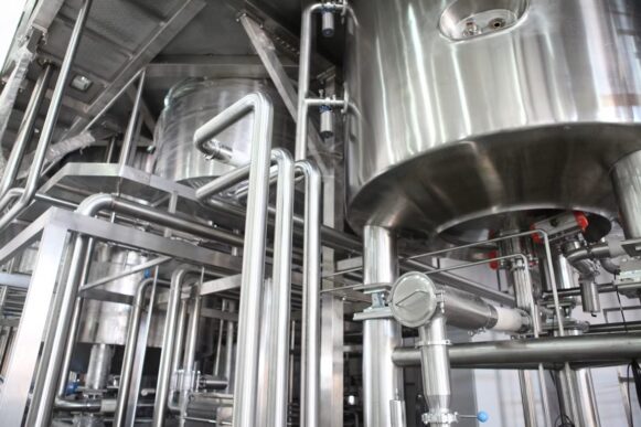 Stainless steel processing tanks and piping in an industrial facility, illustrating chemical manufacturing pricing and margin control.
