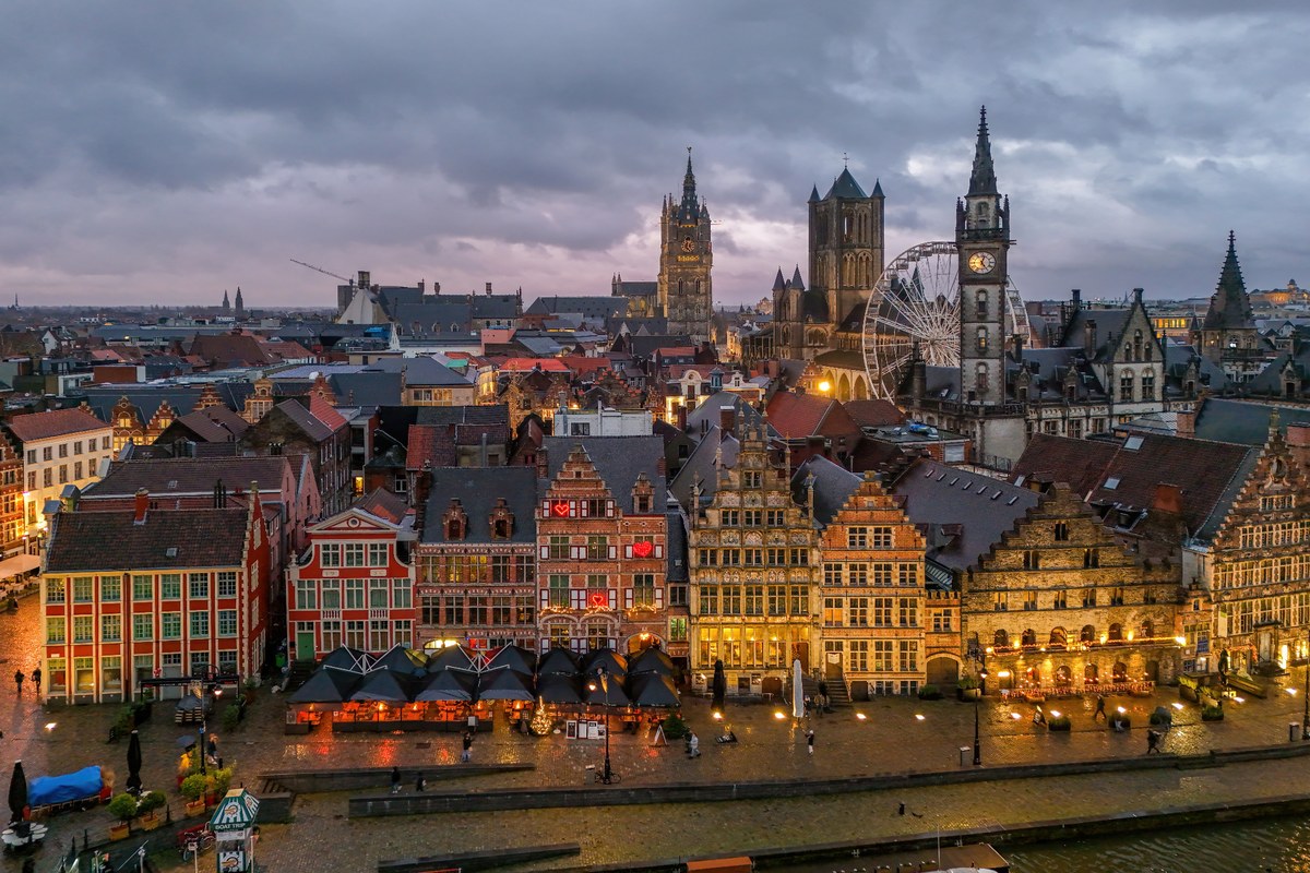 Ghent skyline at dusk with Graslei, Saint Nicholas’ Church, the Belfry, and historic buildings near Tekst’s headquarters.
