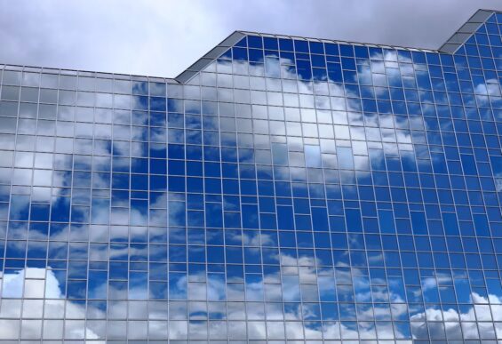 Glass office building reflecting clouds, illustrating cloud-based SAP modernization and distributed operational responsibility.