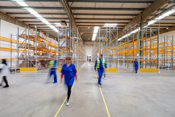 Warehouse workers moving through aisles in a modern distribution facility, representing connected SAP operations
