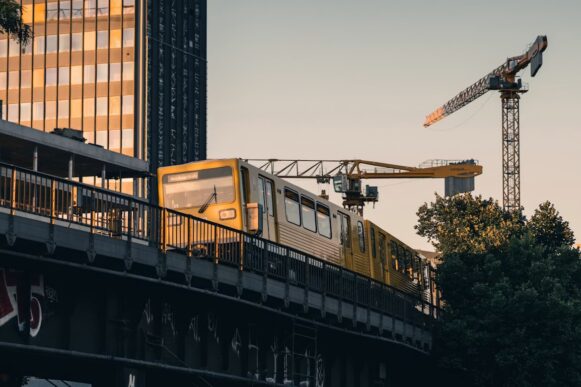 Yellow Berlin train passes construction cranes near Camunda’s home city, illustrating enterprise AI agents moving toward production.