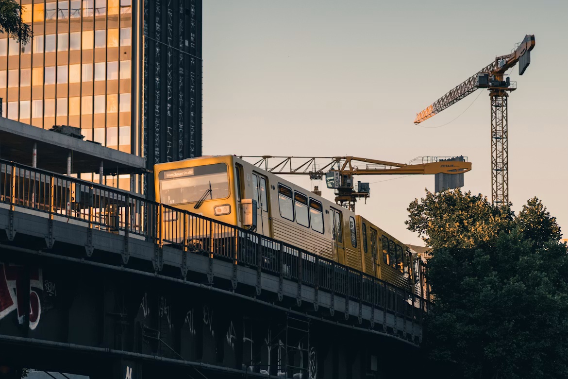 Yellow Berlin train passes construction cranes near Camunda’s home city, illustrating enterprise AI agents moving toward production.
