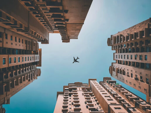 Airplane flying above buildings in Noida, India, representing Denpro Technologies’ SAP consulting operations.