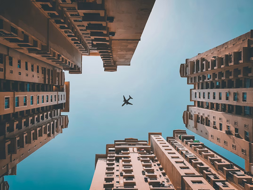 Airplane flying above buildings in Noida, India, representing Denpro Technologies’ SAP consulting operations.