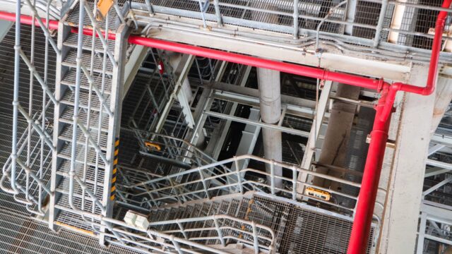 Industrial steel stairways and red piping representing complex SAP Industry AI operations and interconnected business processes.