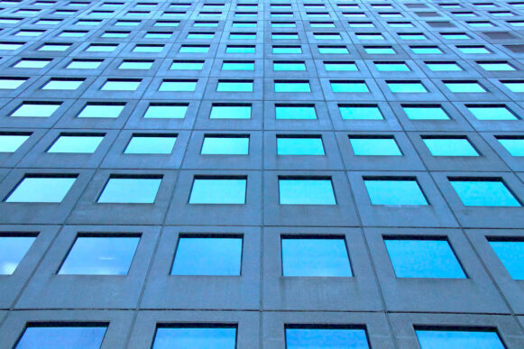 Blue high-rise building facade with repeating windows representing structured AI identity access and governance.