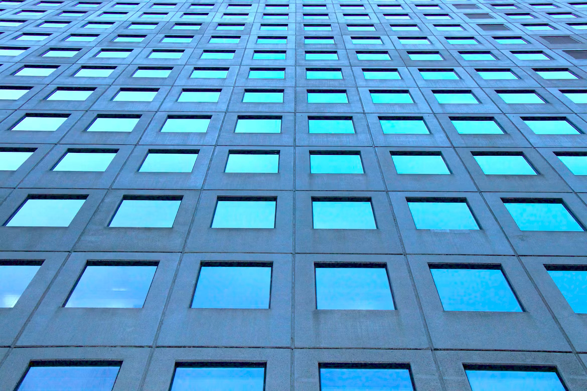 Blue high-rise building facade with repeating windows representing structured AI identity access and governance.