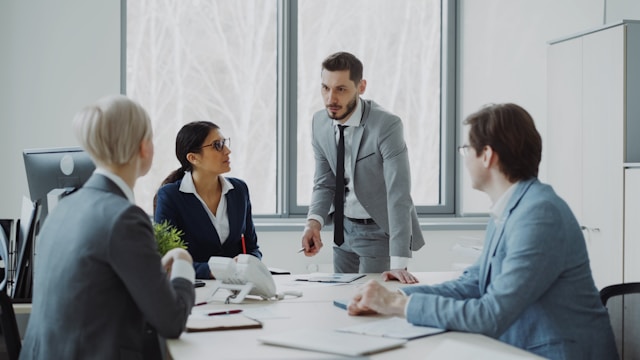 Executives in business suits engaged in a boardroom discussion around a conference table, representing the CIO board interactions and advisory committee dynamics Martin Menard describes