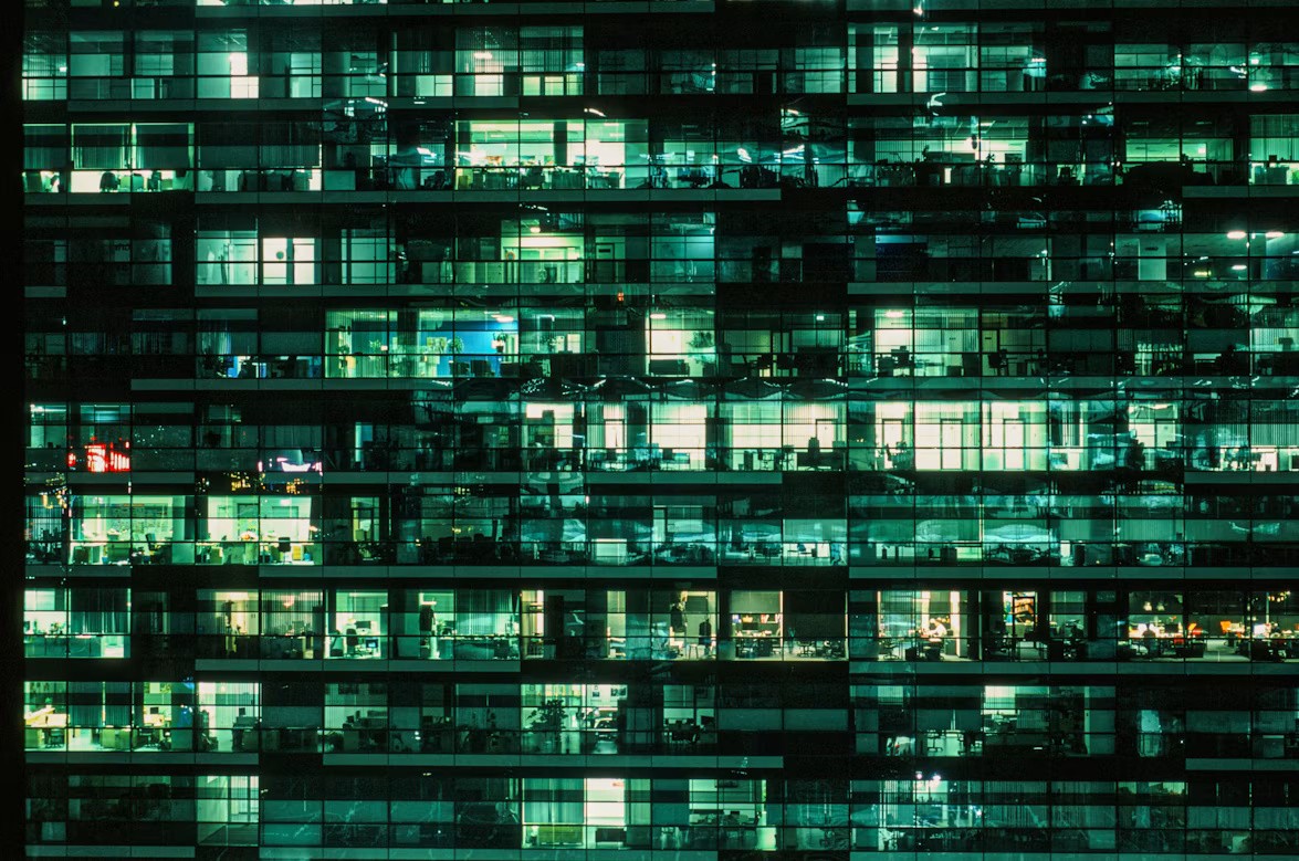 Illuminated office building windows at night, used as a metaphor for selective data access in SAP Datasphere.