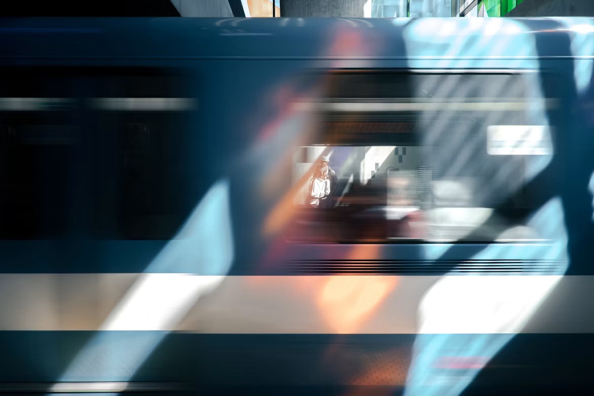 Blurred blue train passing a waiting commuter, illustrating the accelerating pace of AI cyber risk.