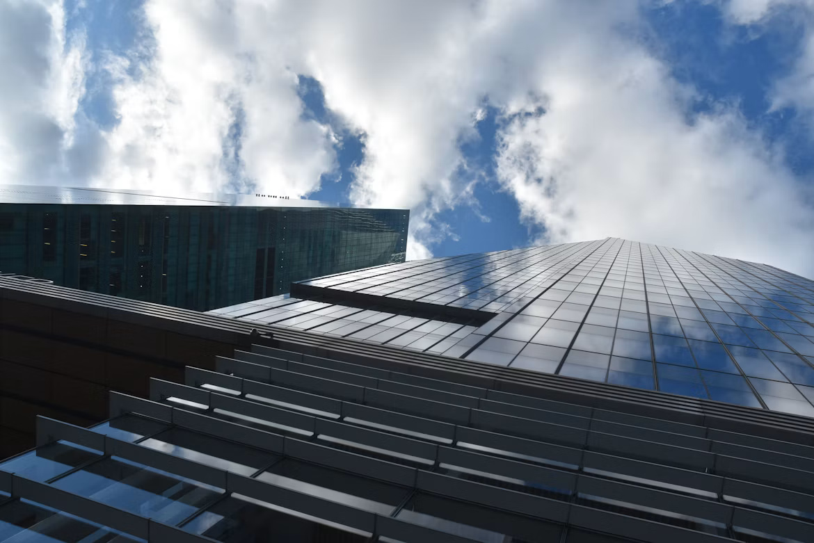 Modern office buildings beneath cloud-filled skies, illustrating hybrid cloud orchestration and enterprise infrastructure