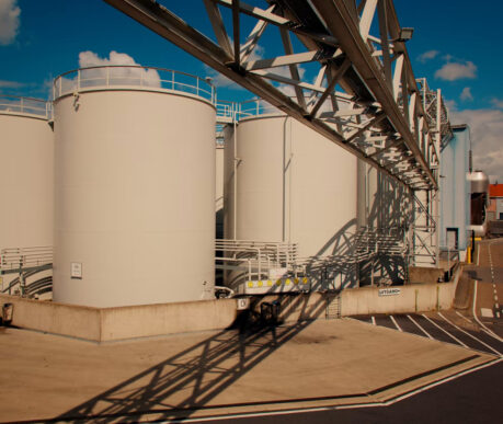 Industrial fuel storage tanks and piping infrastructure in Antwerp, Belgium, representing global pricing operations in the fuel and lubricants sector.
