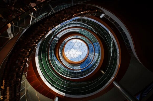 Circular glass atrium with layered architecture and a hexagonal skylight, illustrating complexity and interconnected enterprise systems.
