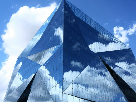 Clouds reflected across a modern glass office building, illustrating SAP Cloud ALM and complex enterprise operations.